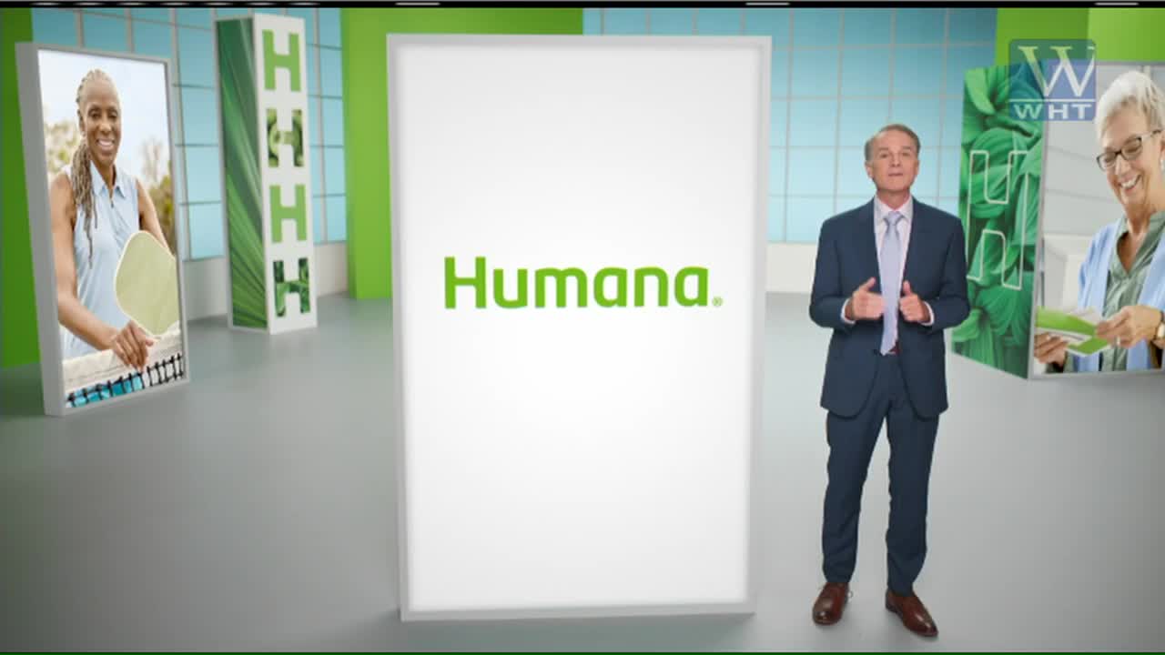 A man in a suit stands in front of a giant "Humana" logo on World Harvest TV. On either side, images of people are displayed, one playing a sport and the other looking at paperwork.

