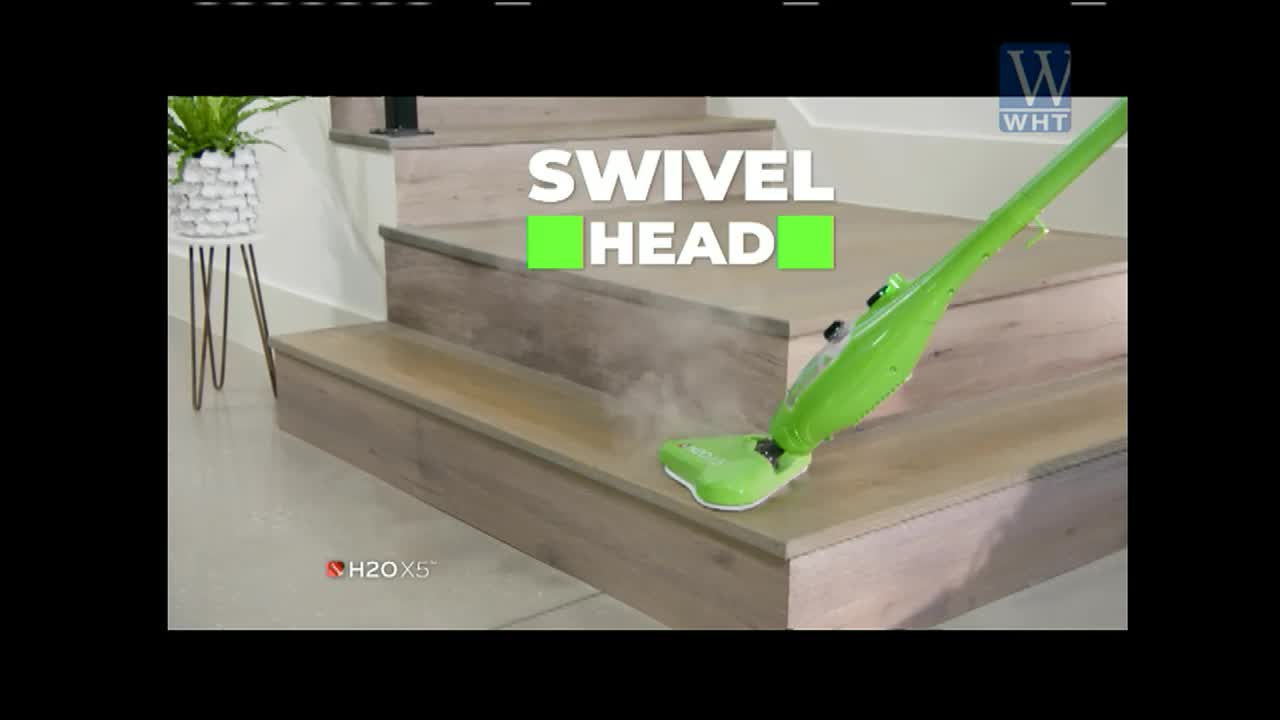 A bright green steam mop is gliding across a wooden stair tread, leaving a trail of vapor in its wake. The "Swivel Head" is highlighted in a graphic on what appears to be a World Harvest TV commercial.
