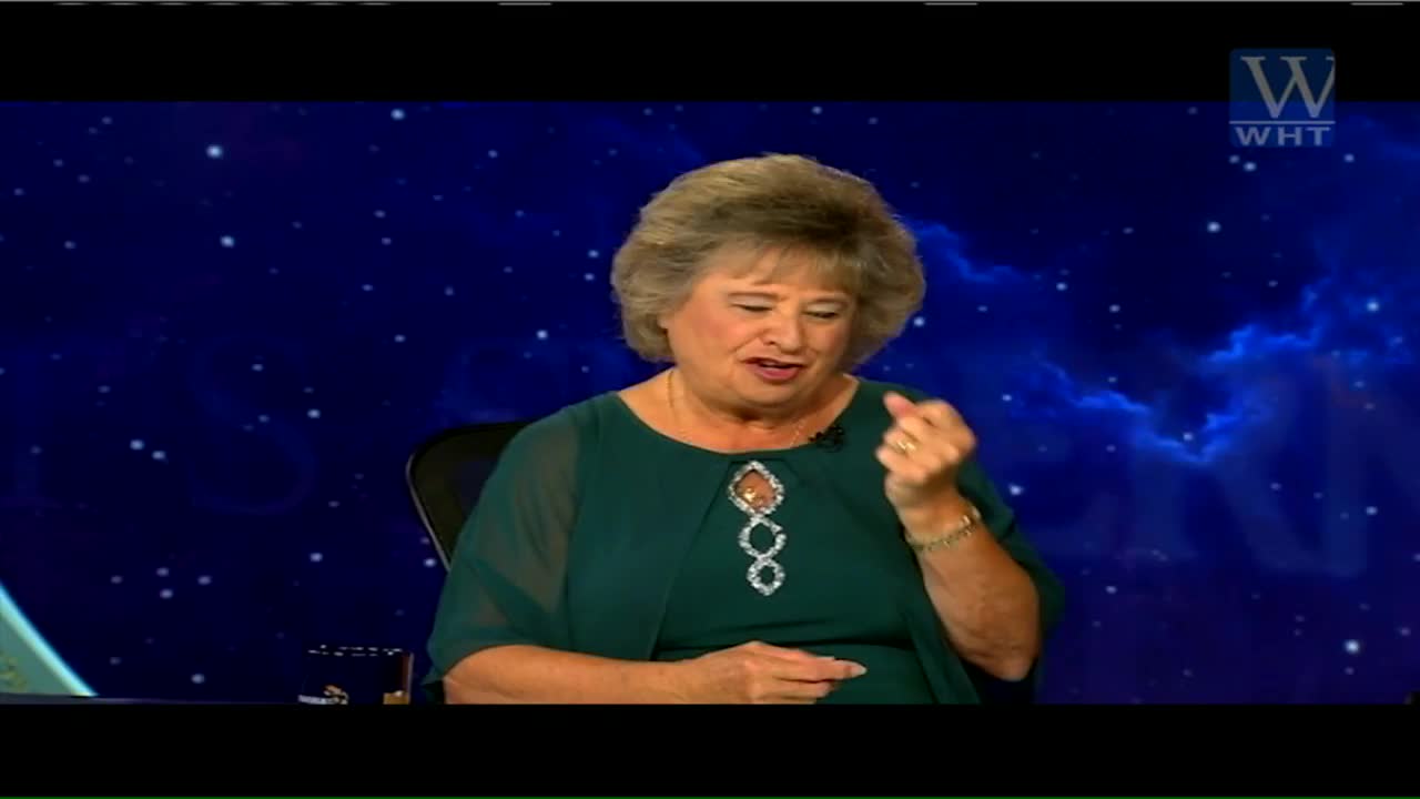 The woman in the green dress is speaking, her right hand clenched in a fist. Behind her, a blue backdrop with a starry design and the World Harvest TV logo fills the screen.
