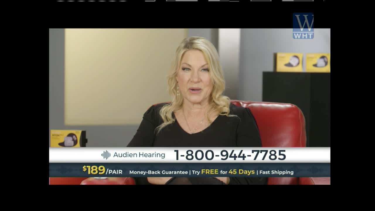 A woman with blonde hair sits in a red chair, speaking directly to the camera. A graphic displays "Audien Hearing" and a phone number.