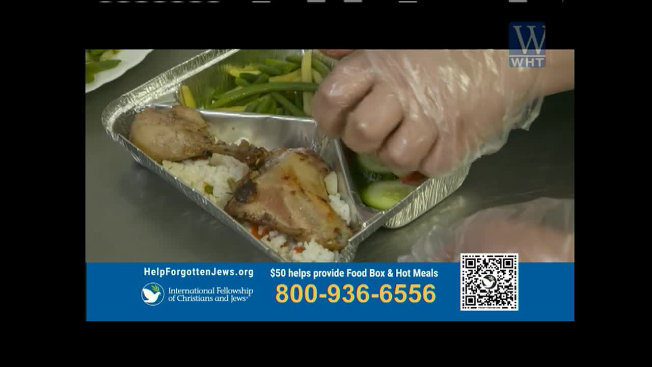 Gloves are being used to place cucumber slices into a foil container of food. The meal includes chicken pieces and rice, with green beans on the side.