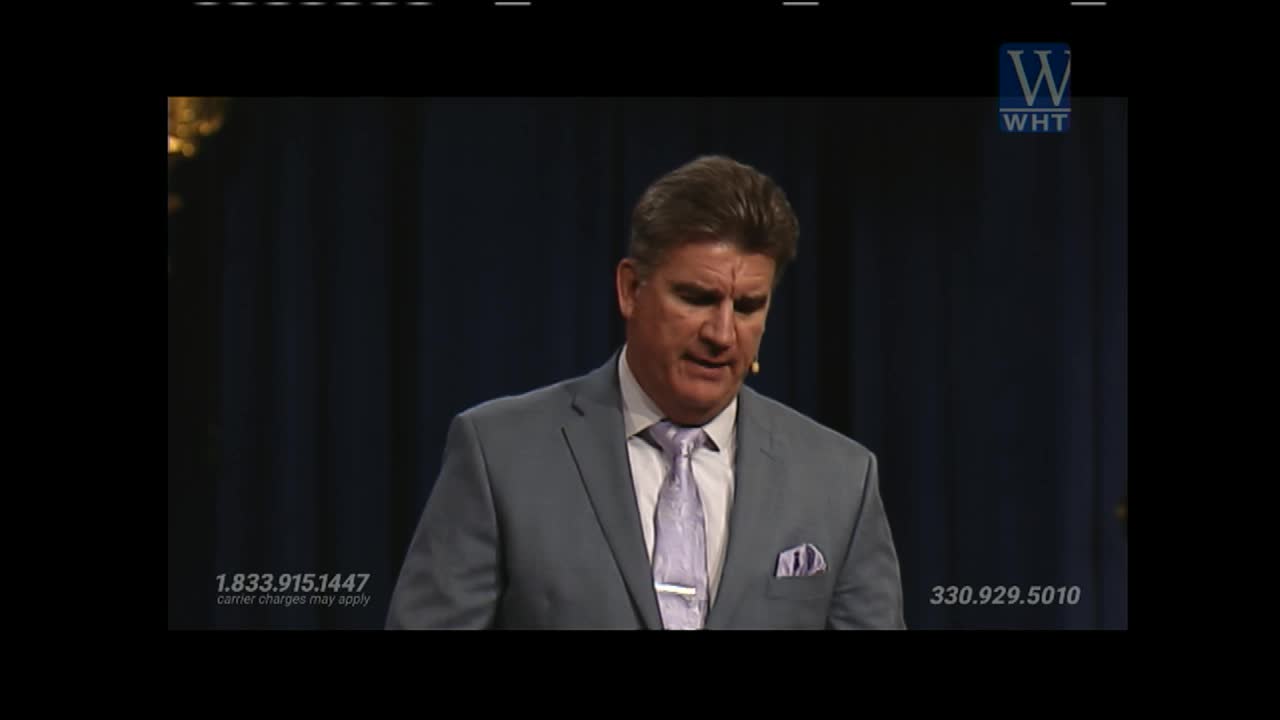 A man in a light gray suit and a patterned tie stands before a dark blue curtain, speaking. A logo for World Harvest TV appears in the upper right corner.