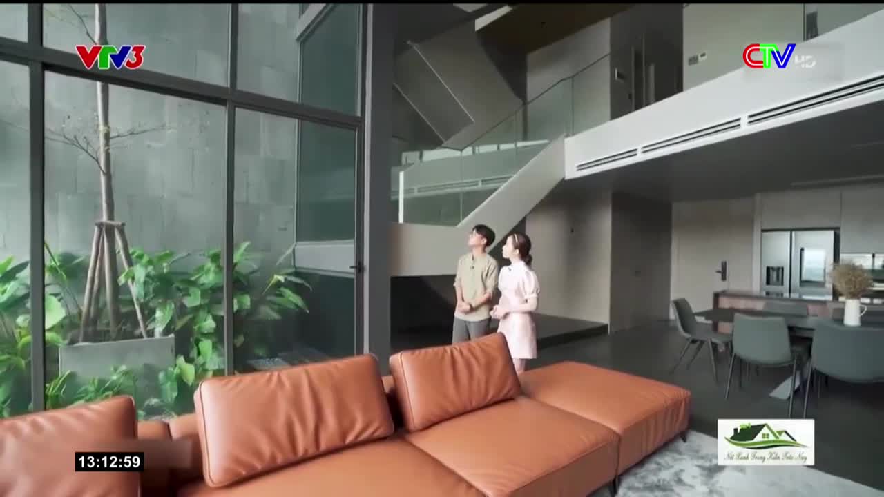 A man and woman stand in a modern, open-plan living space, looking upward. The scene is broadcast on Vietnamese television, with the VTV3 and CTV logos visible.
