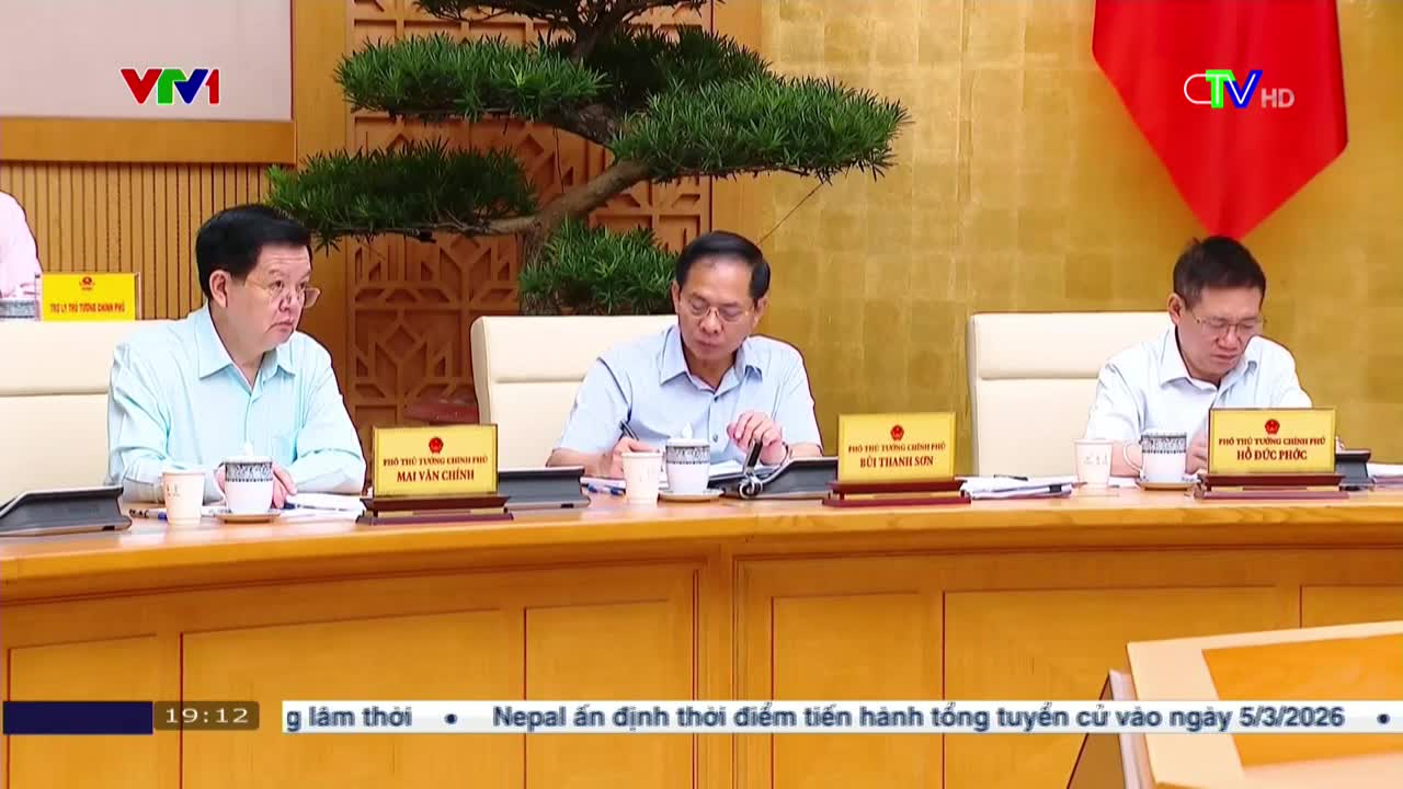 Three men sit at a long wooden table, each with a nameplate in front of them. The broadcast from Bac Lieu TV shows them in a meeting, with a news ticker scrolling across the bottom of the screen.

