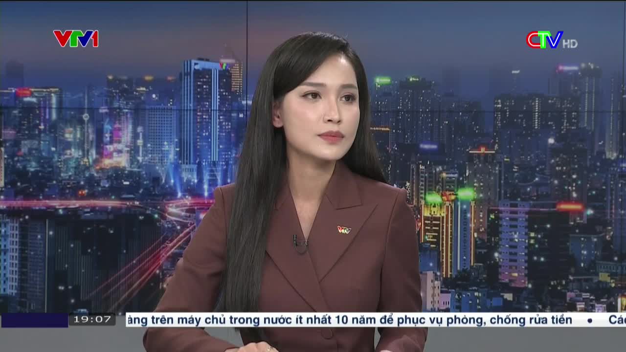 A woman with dark hair and a brown suit sits at a desk, looking directly ahead. Behind her, a cityscape glows with lights, and the VTV logo is visible in the upper left corner.
A woman with dark hair and a brown suit sits at a desk, looking directly ahead. Behind her, a cityscape glows with lights, and the VTV logo is visible in the upper left corner.