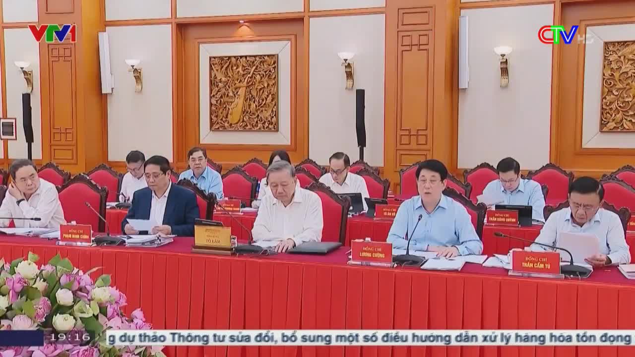 A group of men in shirts and jackets sit around a long table, papers in front of them. The Ca Mau TV logo is visible in the corner, and the bottom of the screen displays text in Vietnamese.
