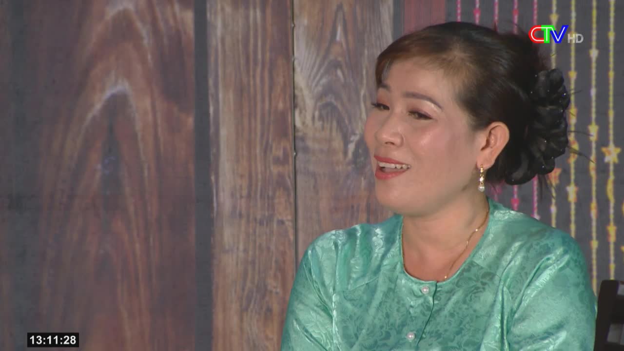 A woman in a teal blouse is speaking, her face lit up with a smile. The Ca Mau TV logo is visible in the corner, and the time reads 13:11:28.
