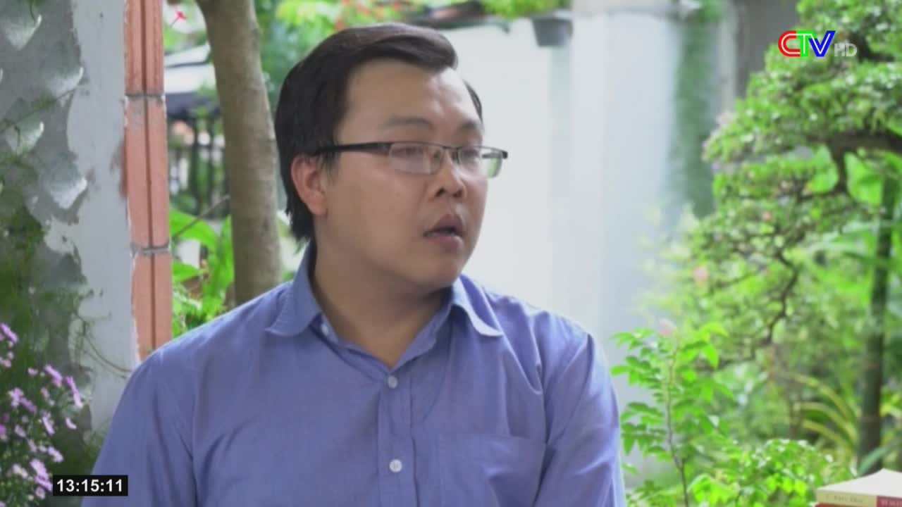 A man in a blue shirt and glasses is looking off-camera, his mouth slightly open. The Ca Mau TV logo is visible in the corner, and the time is displayed on the screen.
