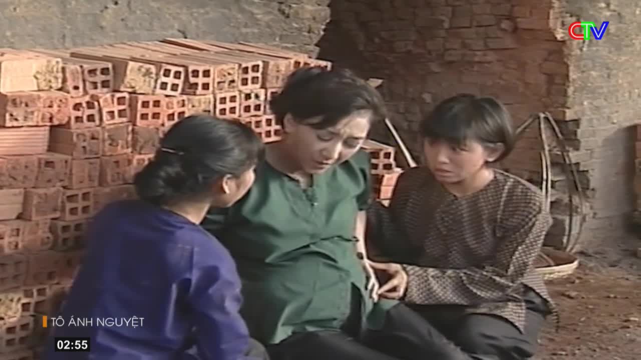 A pregnant woman, her face etched with concern, leans forward as two younger women offer support. They sit amidst stacks of rough, unbaked bricks, the air thick with the scent of earth and the quiet hum of the Ca Mau countryside.