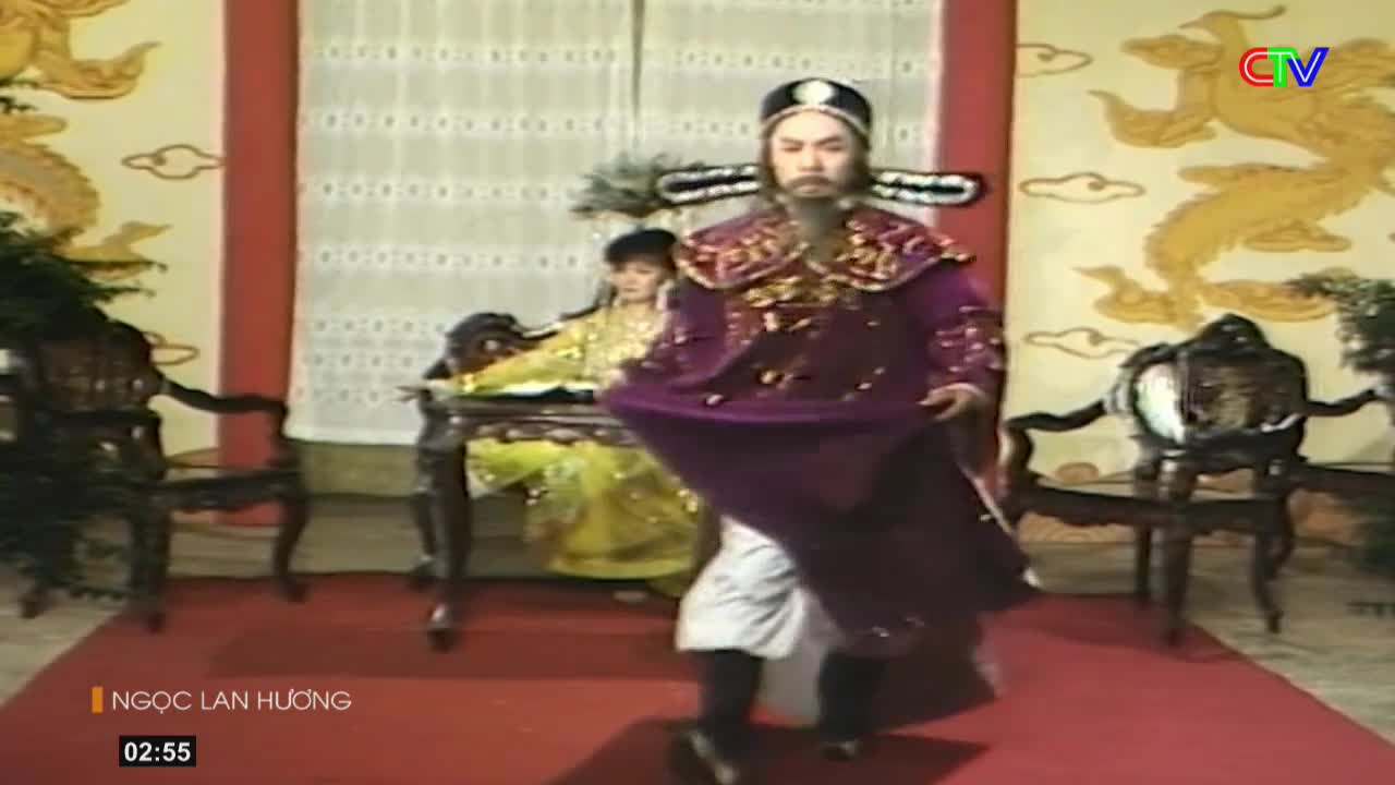 A man in a rich purple robe strides forward, his long beard flowing. Behind him, a woman in a shimmering yellow outfit sits at a table, her gaze fixed forward.