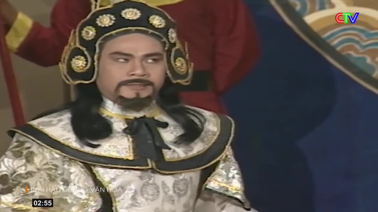 A man in ornate historical costume, with a black beard and elaborate headdress, turns his head to the right. Behind him, figures in red and blue robes stand on a stage, a CTV logo visible in the upper right corner.