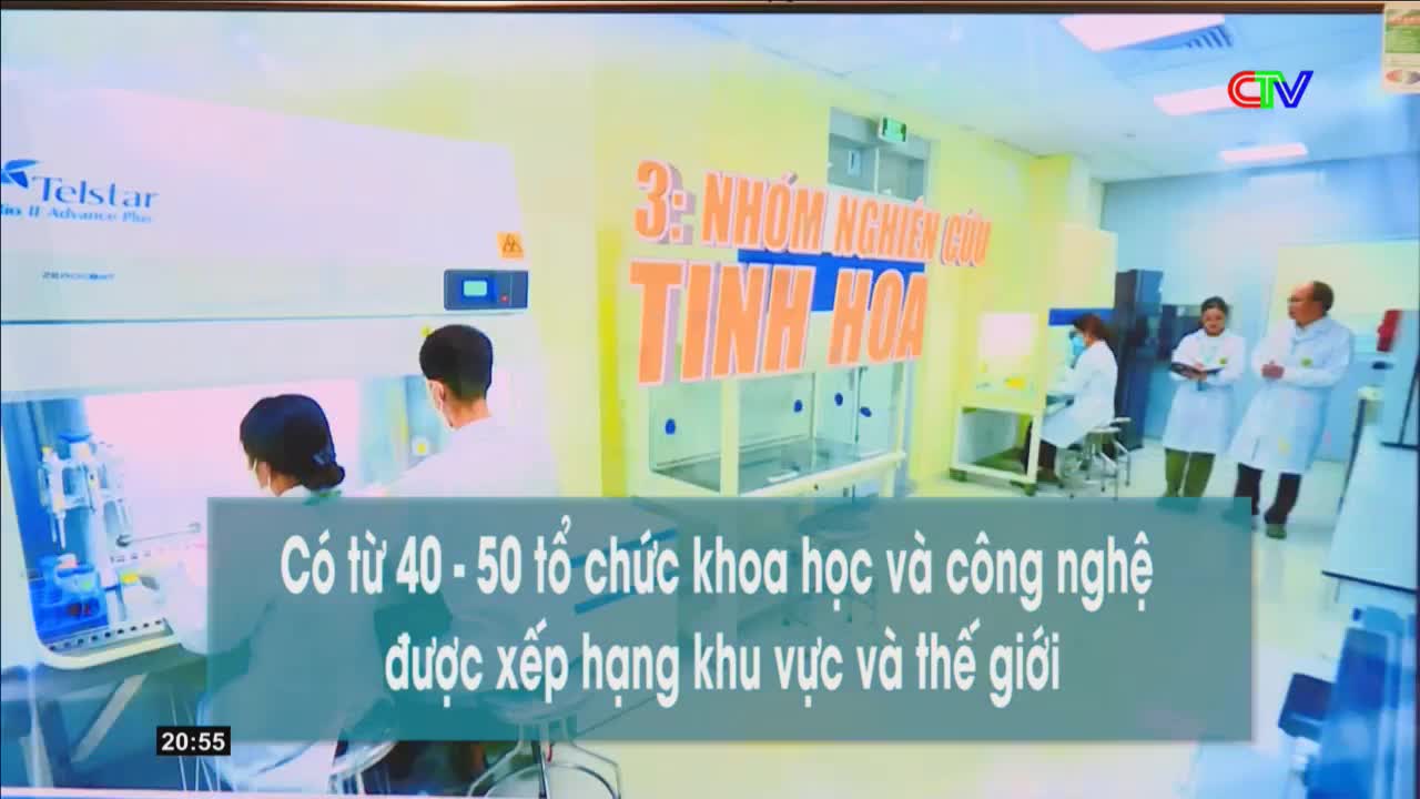 Two scientists in white coats work inside a sterile laboratory hood. Behind them, three other individuals in lab coats stand talking, with a large banner reading "3rd Group of Excellent Research" in Vietnamese overhead. The Ca Mau TV logo is visible in the upper right corner.