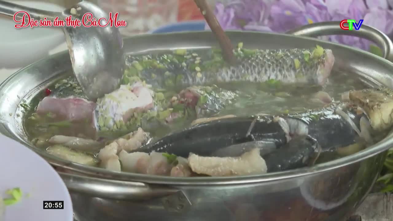 A large pot of steaming broth bubbles with chunks of fish and pork. A ladle dips into the savory mixture, preparing to serve a taste of Ca Mau's culinary traditions.