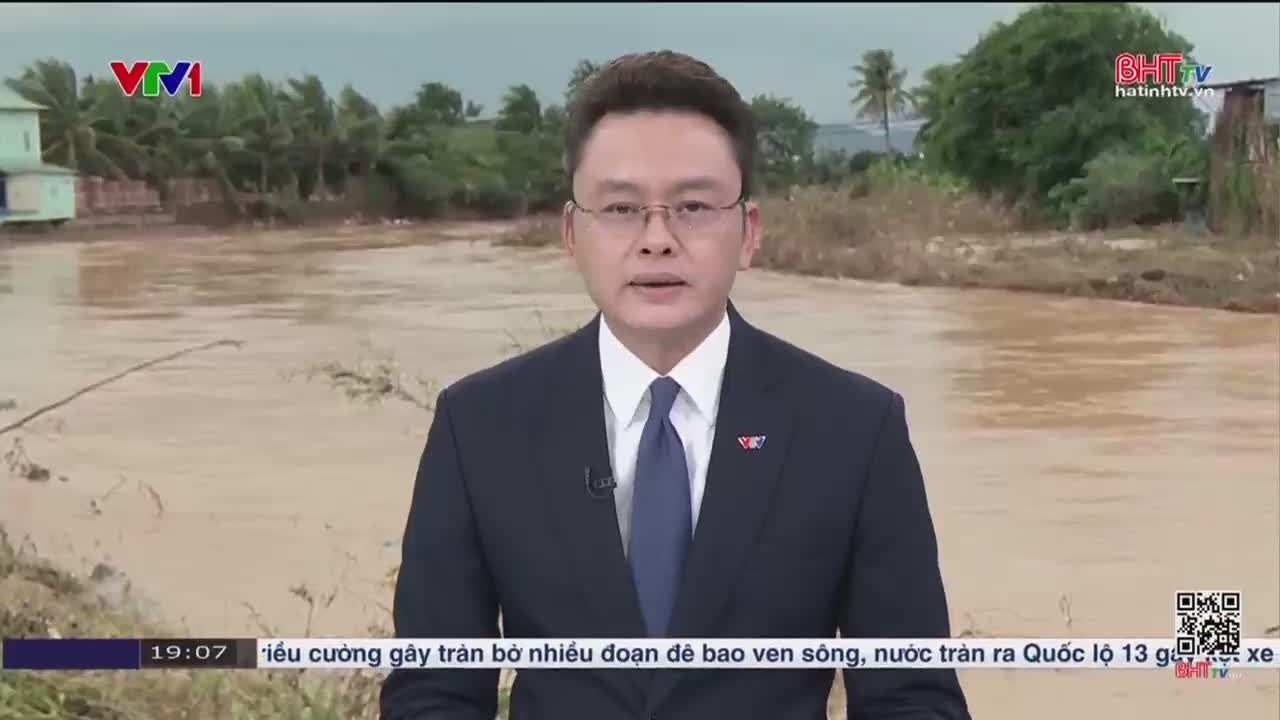 A man in a suit speaks directly to the camera, with a flooded landscape behind him. The water, a muddy brown, covers the land, and the scene is being broadcast on Ha Tinh TV in Vietnam.
A man in a suit speaks directly to the camera, with a flooded landscape behind him. The water, a muddy brown, covers the land, and the scene is being broadcast on Ha Tinh TV in Vietnam.