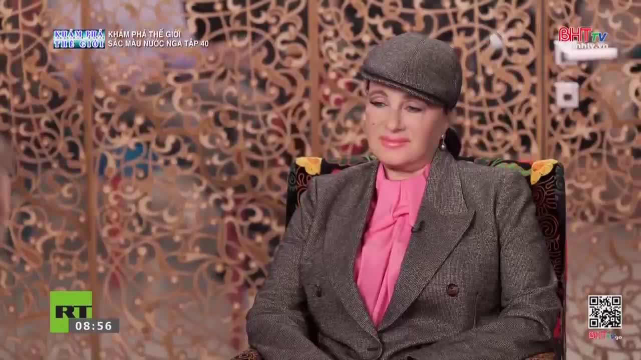 A woman in a grey cap and jacket sits in a patterned chair. The screen displays the Ha Tinh TV logo and a timestamp of 08:56.