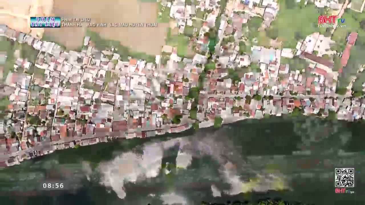 The river water churns and swells, lapping at the edge of a densely packed village. Houses with red tile roofs huddle together along the bank, their foundations disappearing into the murky water.