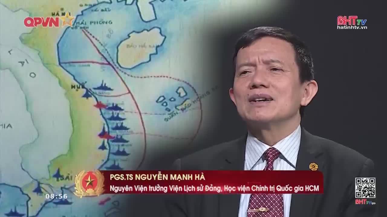A map shows naval vessels lined up along the coast of Vietnam. A man in a suit speaks, his words likely being broadcast by Ha Tinh TV.