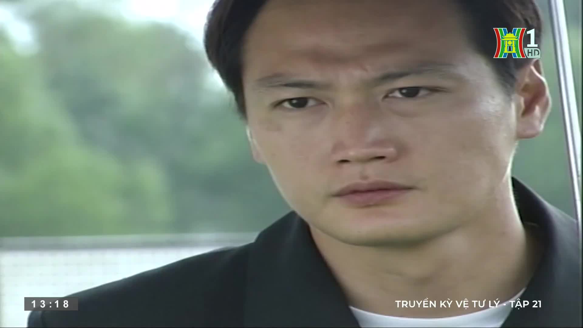 A man stares directly ahead, his expression unreadable as he sits in what looks like a car. The HanoiTV1 logo is visible in the corner, and the Vietnamese title card indicates a television drama.
