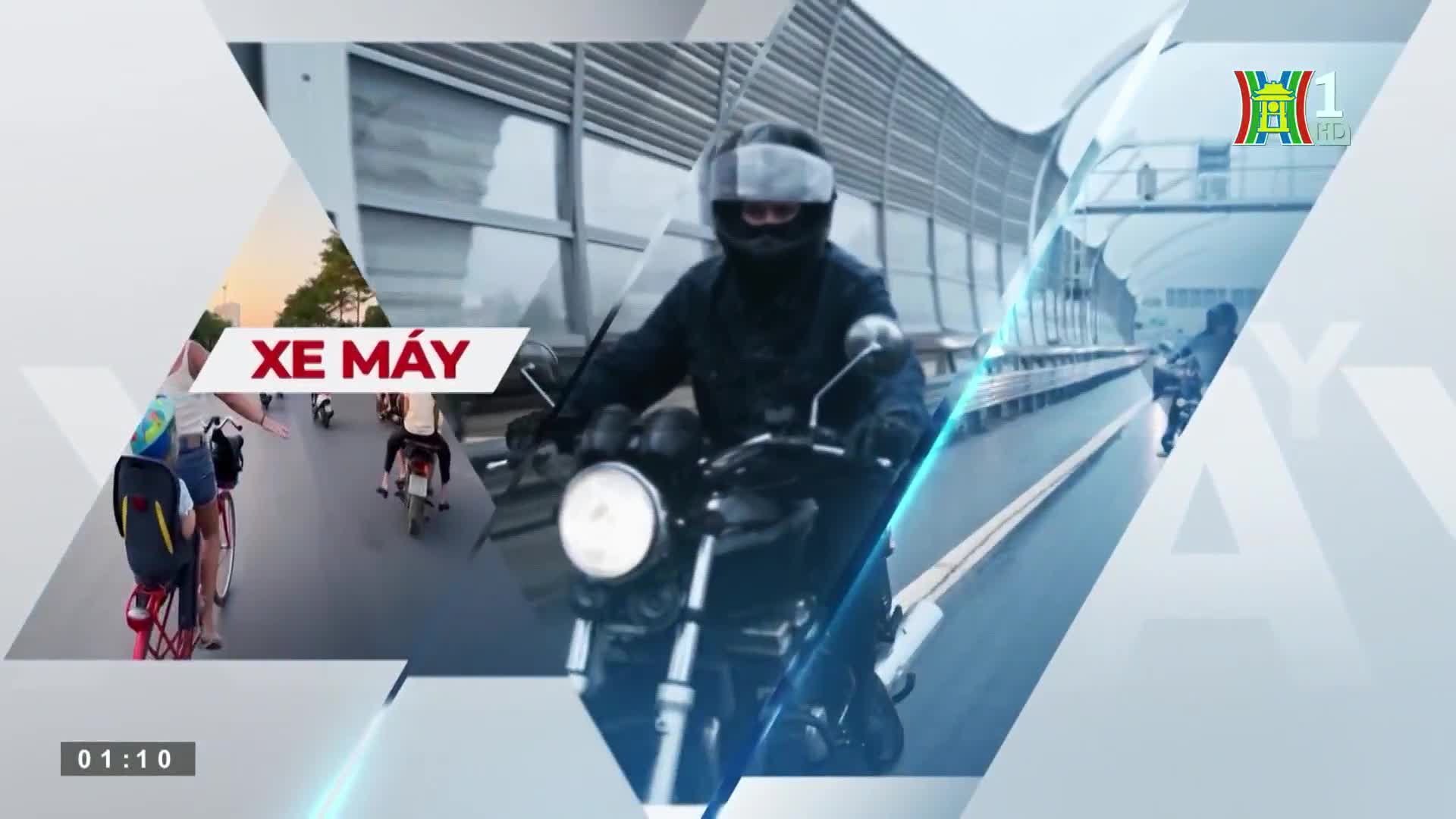 A motorcyclist, clad in a helmet and dark clothing, rides down a wet road. Other vehicles, including bikes and motorbikes, are visible in the inset, which is part of a HanoiTV1 broadcast.
