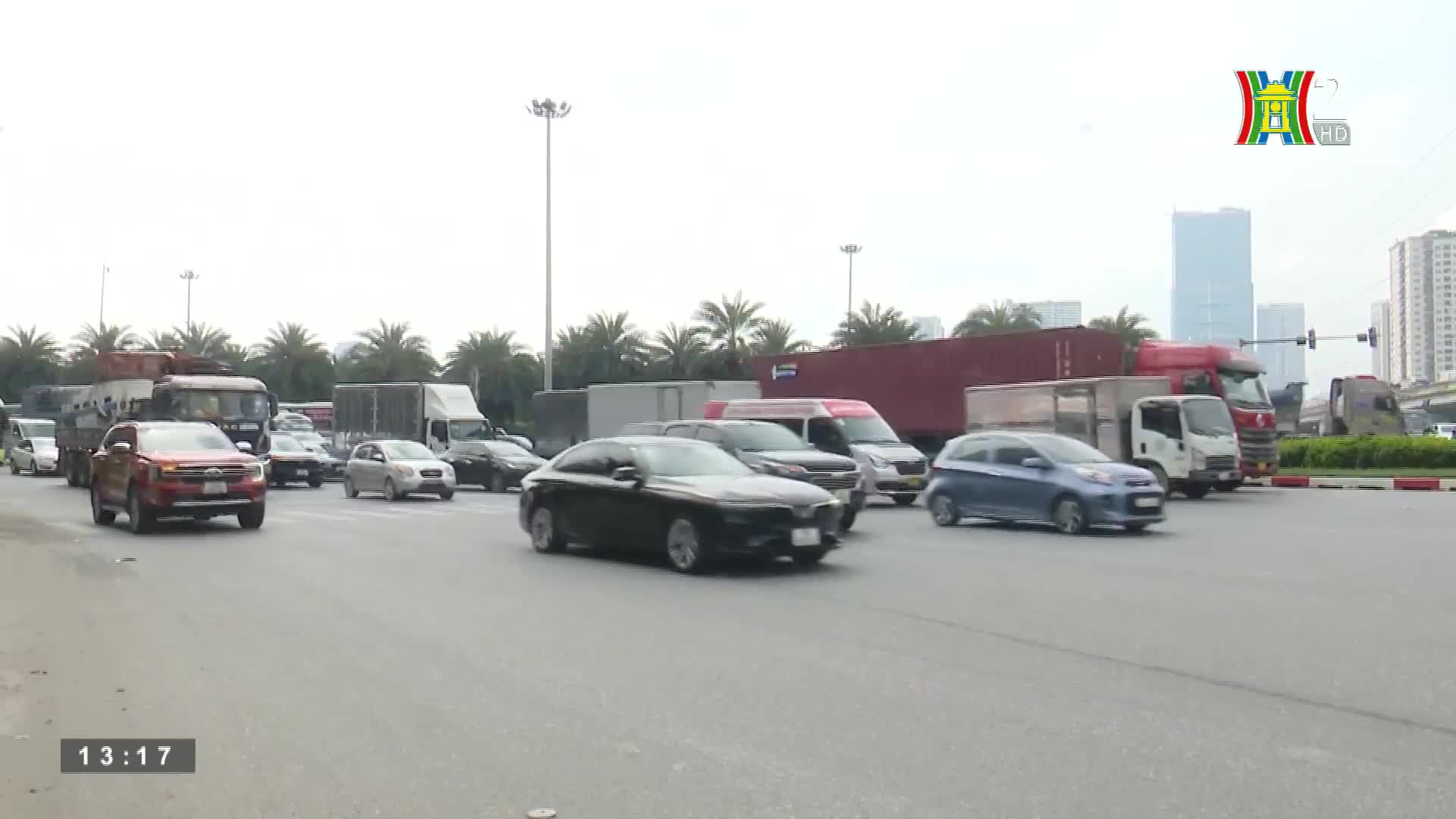 Traffic crawls along a wide road, a mix of cars and trucks inching forward. The HanoiTV2 logo sits in the corner as the vehicles navigate the busy street.
