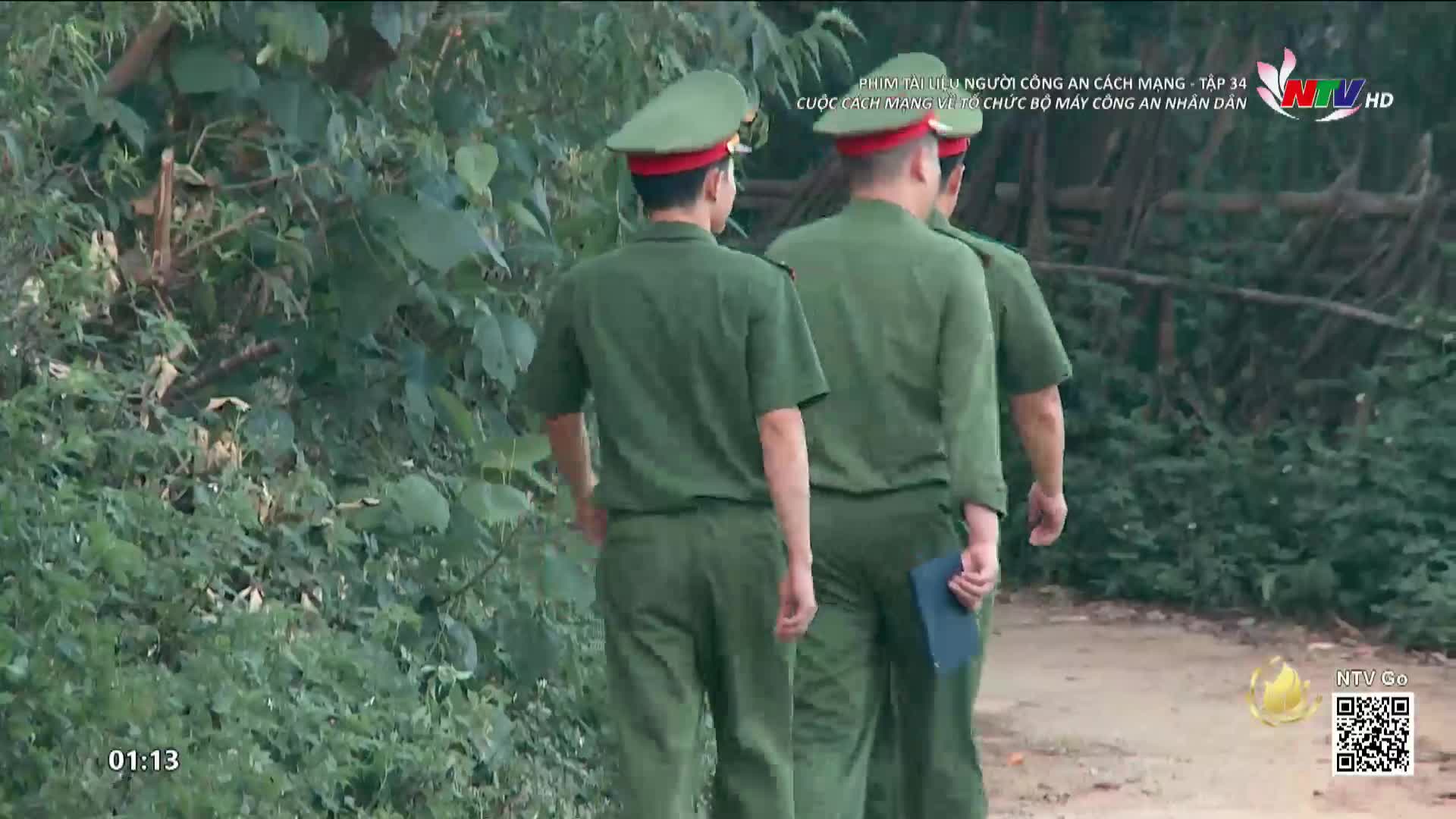 Three men in green uniforms and hats walk down a dirt path, heading away from me. The scene appears to be a segment from a Nghe An TV show, as indicated by the logo in the corner.
