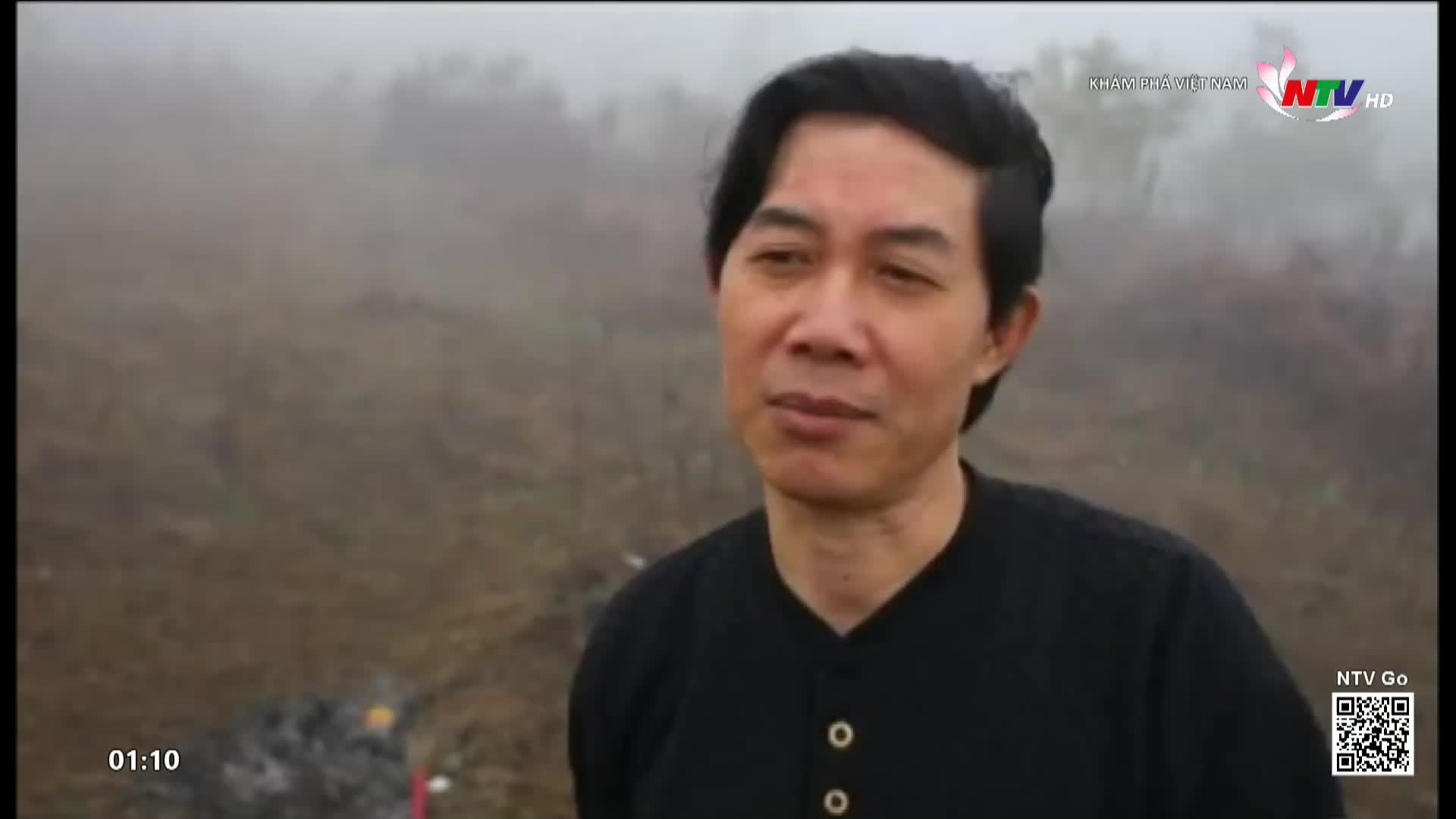 A man in a black shirt stands in front of a misty, brown landscape. The Nghe An TV logo is visible in the corner, and the time reads 01:10.
