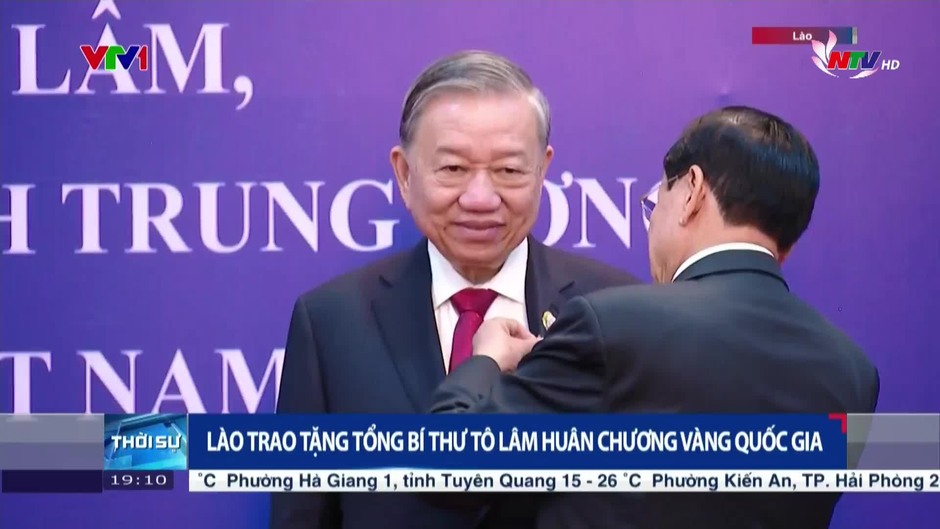 A man in a dark suit is being presented with a medal by another man, who is turned away from the camera. The scene is being broadcast on Nghe An TV, as indicated by the logo.
