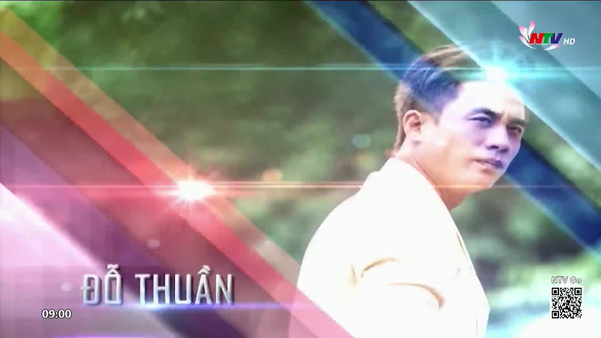 A man with short, dark hair looks intently to his right. Diagonal bands of light and color sweep across the frame, overlaying a soft-focus background of green foliage.