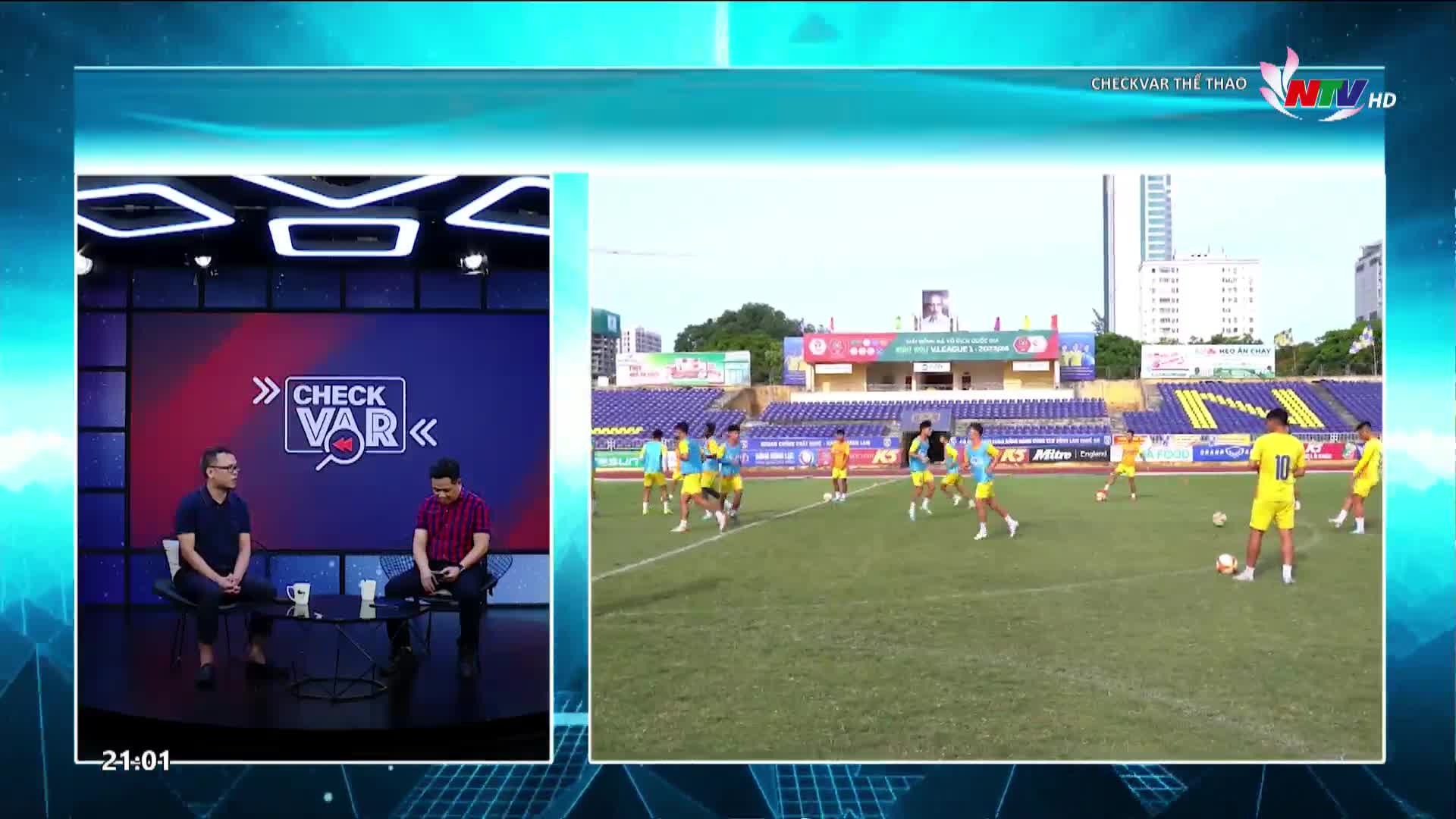 A group of young men in bright yellow jerseys are practicing soccer on a green field, some with balls at their feet. Behind them, stadium seating in blue and yellow stretches out under a bright sky.