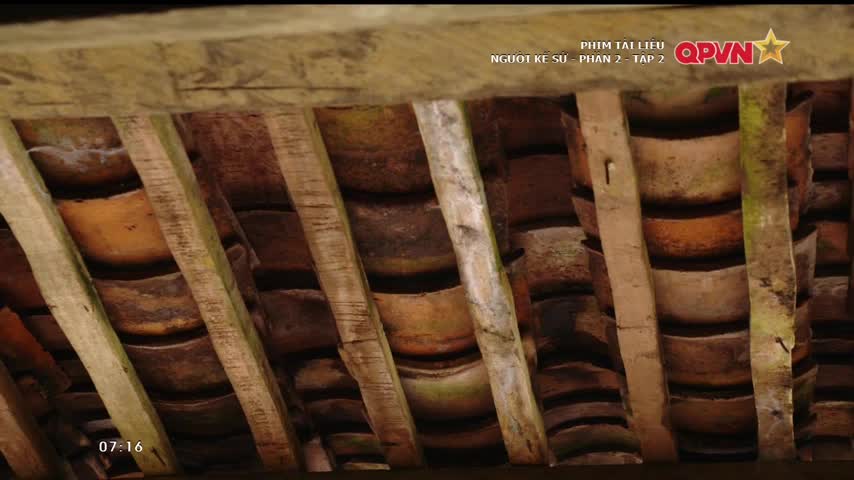 From below, I see the underside of a tiled roof, supported by weathered wooden beams. The curved terracotta tiles are layered, and the beams are spaced apart, creating a grid-like pattern.
