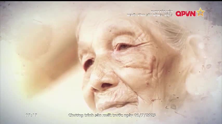 An elderly woman's face fills the screen, her skin etched with the lines of age. The QPVN logo and Vietnamese text are visible in the corner, suggesting a broadcast from Vietnam.

