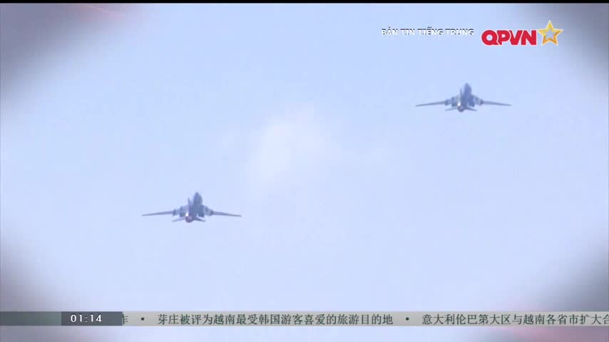 Three fighter jets are flying in formation against a pale blue sky. The QPVN logo is in the top right corner of the screen.
