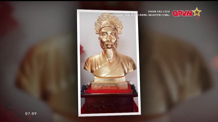 A golden bust of a man with a beard and ornate headwear is framed by a white border. The QPVN logo and Vietnamese text are visible in the top right corner.
