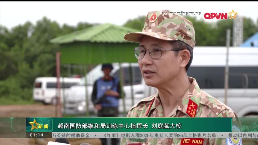 A man in a camouflage cap and glasses speaks, his words framed by a lower-third graphic from QPVN. Behind him, a person in a blue vest stands near a white van, the scene taking place outdoors in Vietnam.
A man in a camouflage cap and glasses speaks, his words framed by a lower-third graphic from QPVN. Behind him, a person in a blue vest stands near a white van, the scene taking place outdoors in Vietnam.