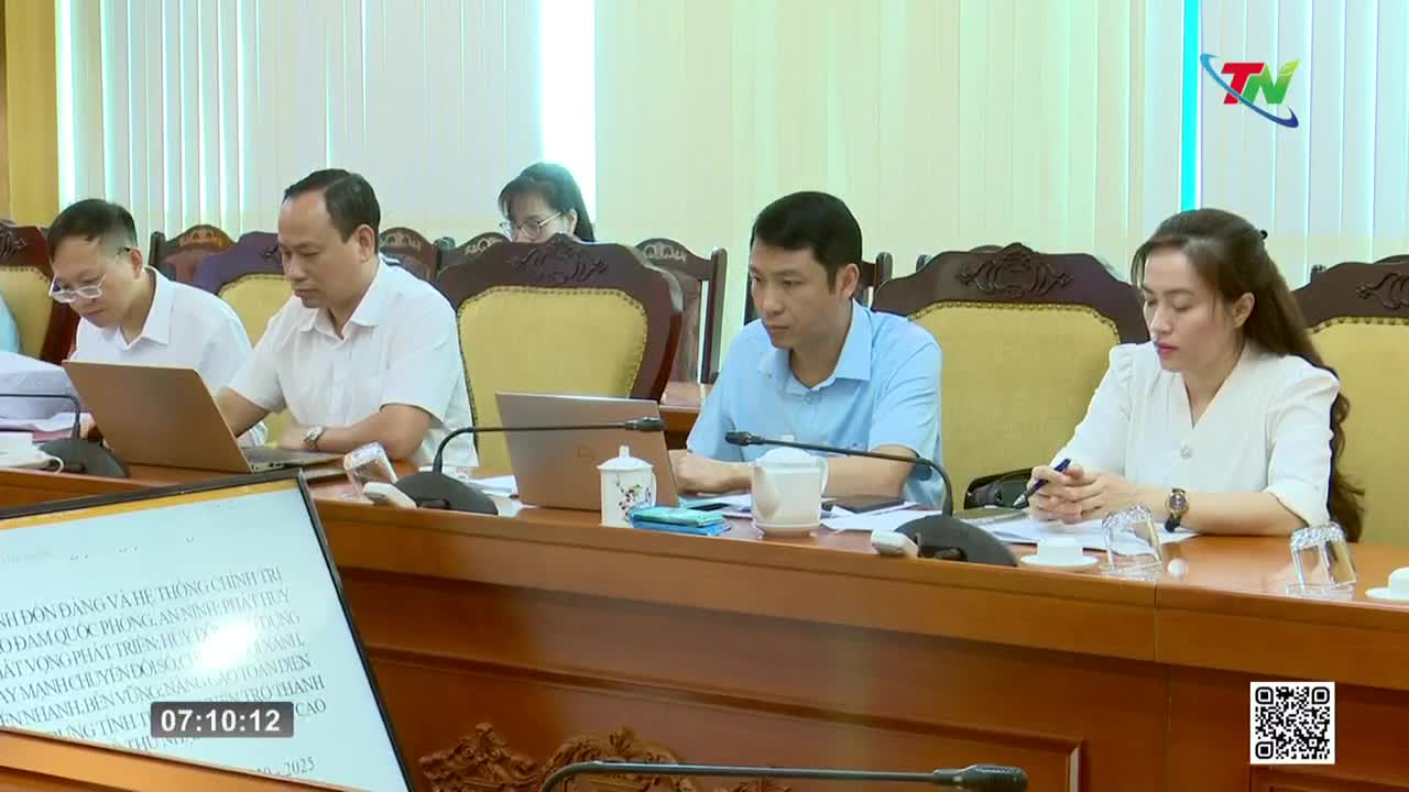 A meeting is underway, with several people seated around a long wooden table, each with a laptop open in front of them. The Thai Nguyen TV logo is visible in the corner, and the time is displayed on a screen.

