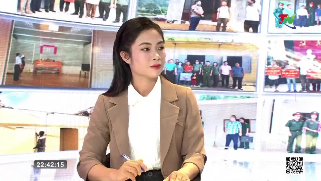 A woman in a tan blazer, holding a pen, looks toward the camera while a screen behind her displays various scenes. The Thai Nguyen TV logo is visible in the corner.
