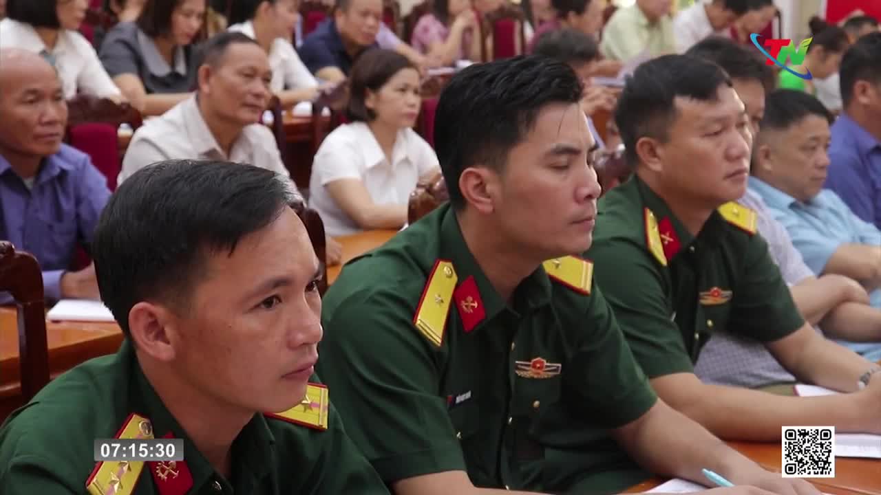 A group of men in military uniforms sit attentively, alongside civilians, in a large room. The Thai Nguyen TV logo is visible in the corner as the camera focuses on the faces of the audience.
