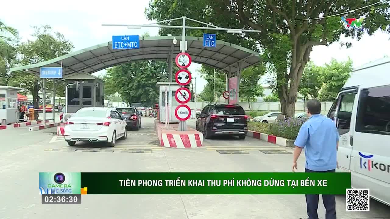 Cars are slowly approaching a toll booth with signs for ETC and MTC lanes, as seen on Thai Nguyen TV. A man in a blue shirt walks towards a white van parked nearby.
