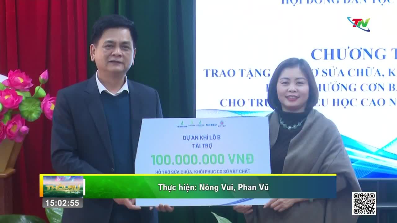 A man and a woman stand holding a large white sign with Vietnamese text. The sign announces a donation of 100,000,000 VND for a project.