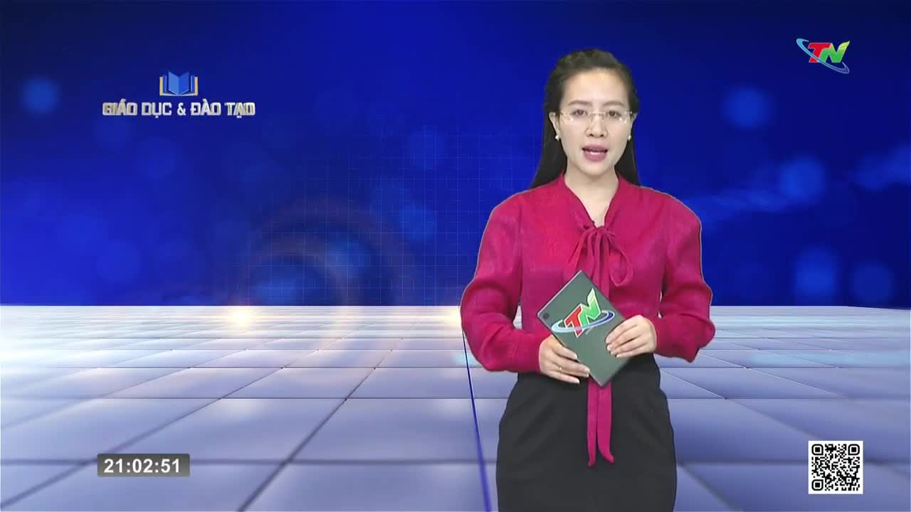A woman in a bright pink blouse stands before a blue screen, holding a tablet with the Thai Nguyen TV logo. The digital clock in the corner reads 21:02:51.