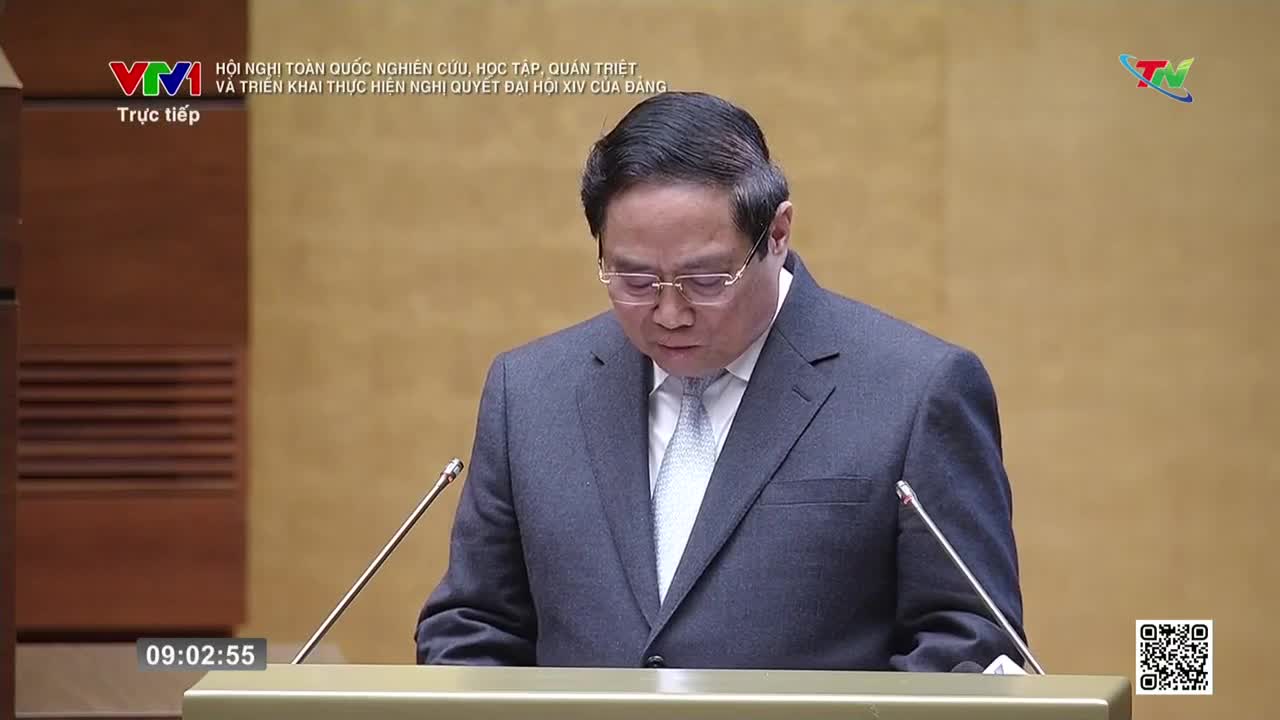 A man in a dark suit stands at a podium, his head bowed as if reading. The VTV logo appears in the upper left corner, indicating a live broadcast.