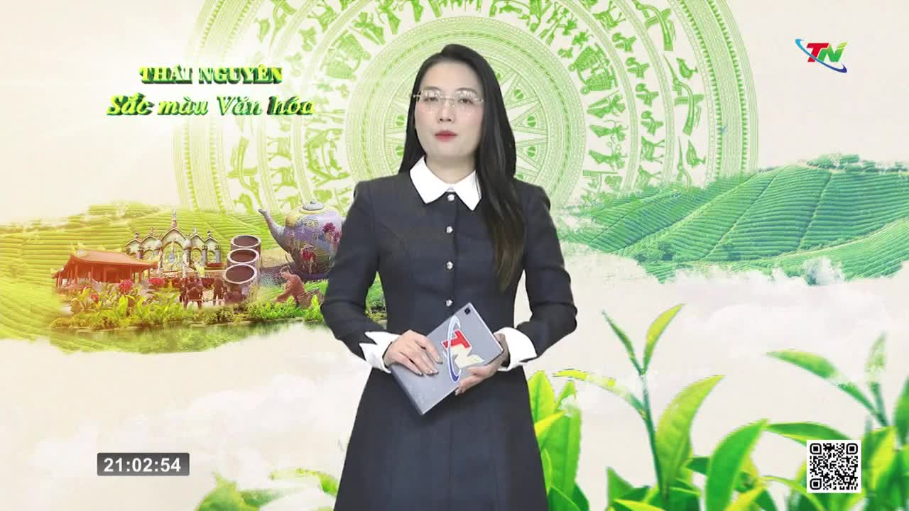 A woman stands before a backdrop of rolling green hills and traditional Vietnamese motifs. She holds a tablet, her expression neutral as the clock on screen reads 21:02:54.