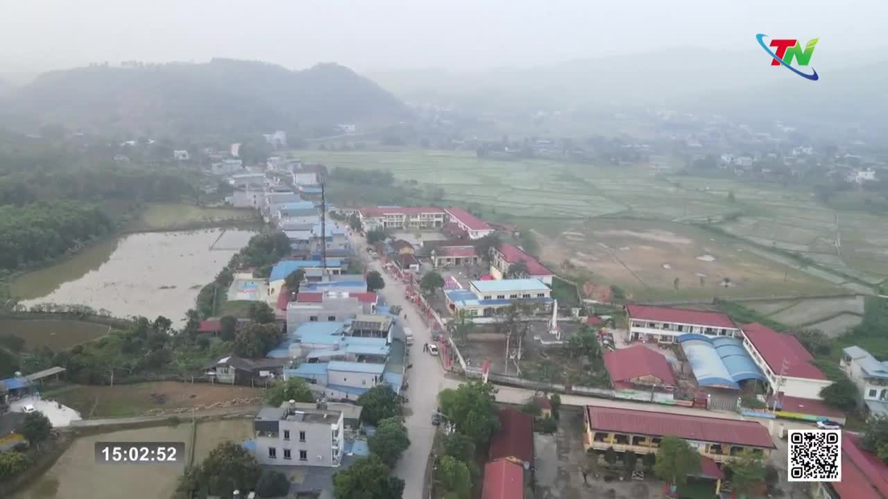 A line of cars and motorbikes moves down the main road, past houses and schools.  Rice paddies stretch out to the right, their green expanse meeting the hazy hills.