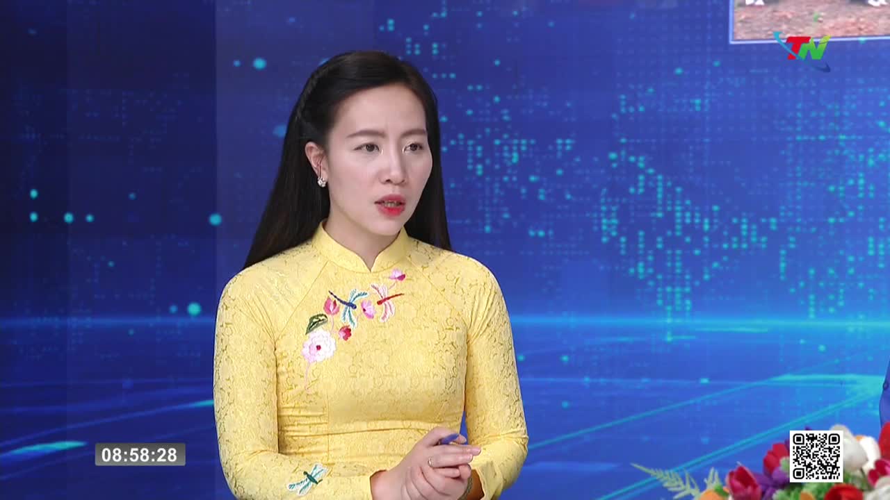 A woman in a bright yellow áo dài speaks on a broadcast from Thai Nguyen TV. The background behind her displays a digital map of the world.
