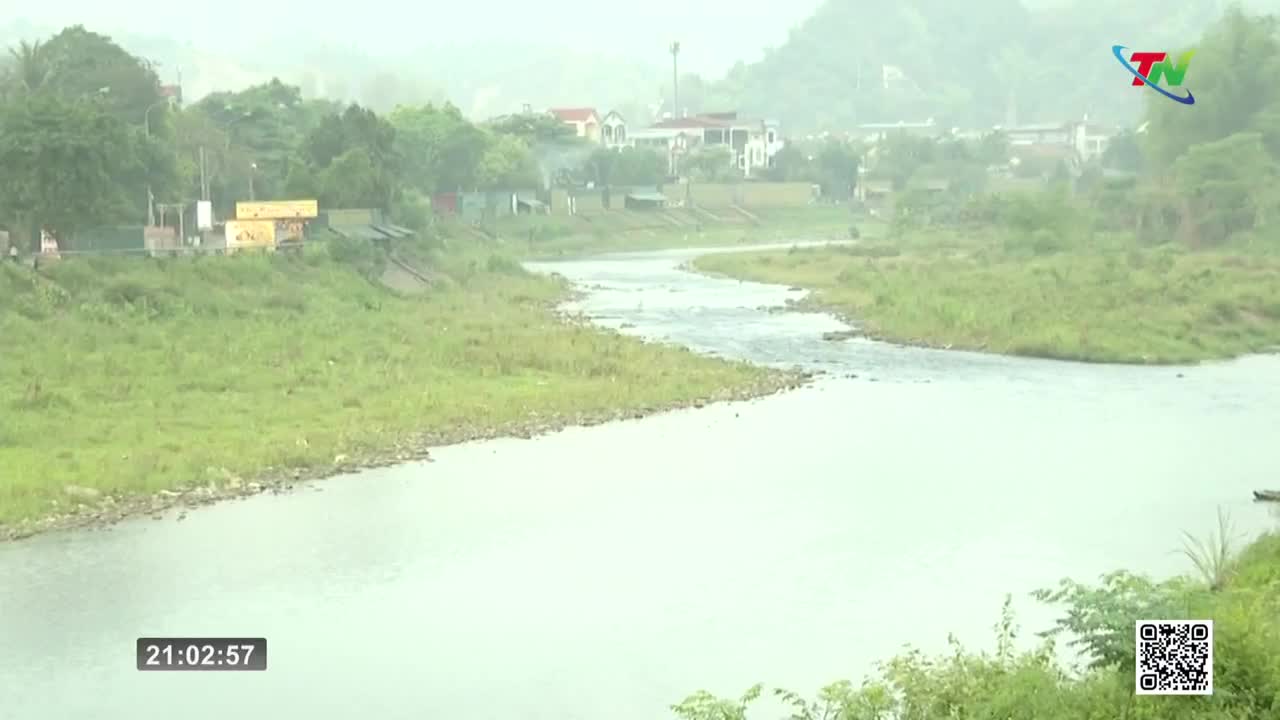 A wide river flows through a green landscape, with houses and trees lining the banks. A small boat drifts on the water's surface. A wide river flows through a green landscape, with houses and trees lining the banks. A small boat drifts on the water's surface.