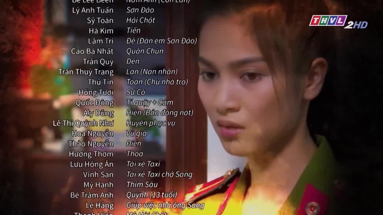 A young woman in a uniform looks to her right, her expression serious. The credits for a show on Tra Vinh TV, with Vietnamese names and roles, are scrolling beside her.
