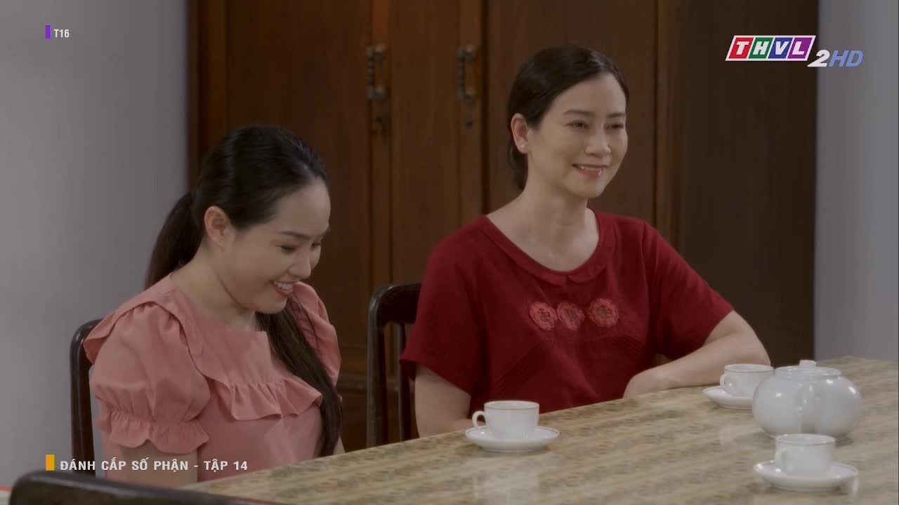 Two women, seated at a table, smile at something beyond the frame. A teapot and cups sit between them, suggesting a quiet moment on Tra Vinh TV.
