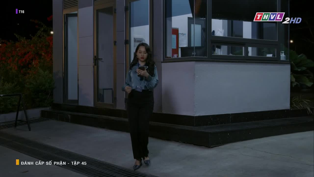 A woman in a denim jacket and black pants walks toward me, eyes glued to her phone. "Danh Cap So Phan" is playing on Tra Vinh TV, episode 45.

