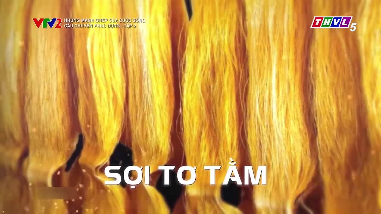 Golden strands of silk, illuminated by a soft light, fill the screen. The text "Sợi Tơ Tằm" is displayed below, likely from a program on Tra Vinh TV in Vietnam.
