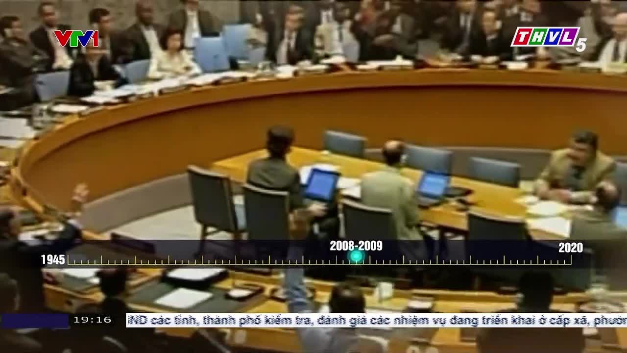 A group of people are seated around a large, curved table with laptops in front of them. The scene is being broadcast on Tra Vinh TV in Vietnam, with a timeline running across the bottom of the screen.
